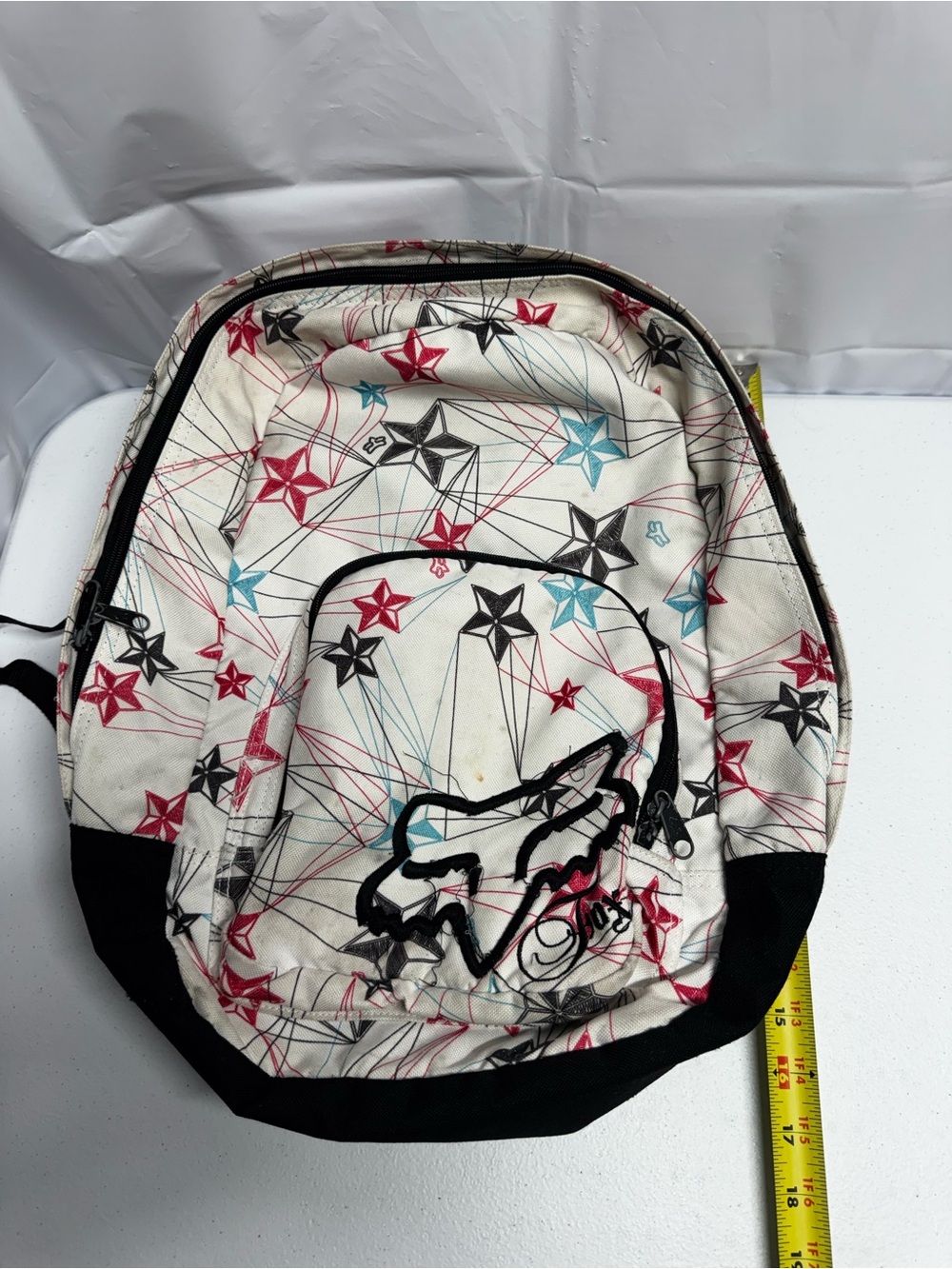 Fox Racing white polyester backpack with red, blue, and black stars and lines